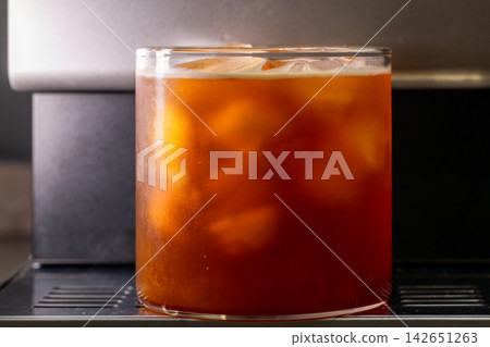 咖啡機將咖啡注入透明冰玻璃杯,在時間的光影中呈現永恆的冰淇淋、咖啡油和暖色光影。 咖啡機將咖啡注入透明冰玻璃杯,在時間的光影中呈現永恆的冰淇淋、咖啡油和暖色光影。 142651263