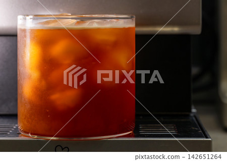 咖啡機將咖啡注入透明冰玻璃杯,在時間的光影中呈現永恆的冰淇淋、咖啡油和暖色光影。 咖啡機將咖啡注入透明冰玻璃杯,在時間的光影中呈現永恆的冰淇淋、咖啡油和暖色光影。 142651264