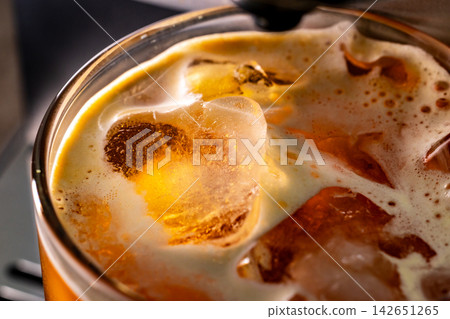 咖啡機將咖啡注入透明冰玻璃杯,在時間的光影中呈現永恆的冰淇淋、咖啡油和暖色光影。 咖啡機將咖啡注入透明冰玻璃杯,在時間的光影中呈現永恆的冰淇淋、咖啡油和暖色光影。 142651265