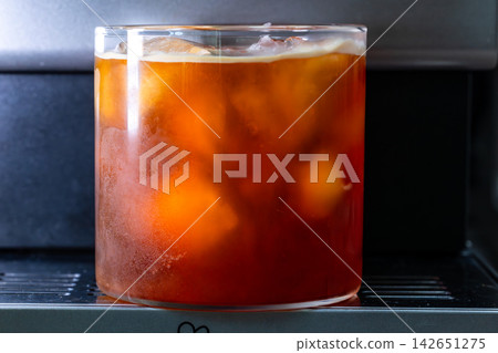 咖啡機將咖啡注入透明冰玻璃杯,在時間的光影中呈現永恆的冰淇淋、咖啡油和暖色光影。 咖啡機將咖啡注入透明冰玻璃杯,在時間的光影中呈現永恆的冰淇淋、咖啡油和暖色光影。 142651275