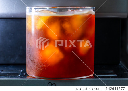 咖啡機將咖啡注入透明冰玻璃杯,在時間的光影中呈現永恆的冰淇淋、咖啡油和暖色光影。 咖啡機將咖啡注入透明冰玻璃杯,在時間的光影中呈現永恆的冰淇淋、咖啡油和暖色光影。 142651277