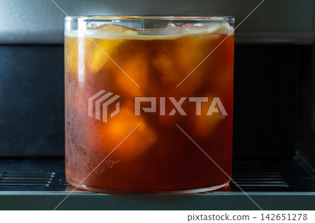 咖啡機將咖啡注入透明冰玻璃杯,在時間的光影中呈現永恆的冰淇淋、咖啡油和暖色光影。 咖啡機將咖啡注入透明冰玻璃杯,在時間的光影中呈現永恆的冰淇淋、咖啡油和暖色光影。 142651278