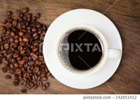 Coffee cup and coffee beans on table / black coffee in white mug on wooden background Coffee cup and coffee beans on table / black coffee in white mug on wooden background 142651412