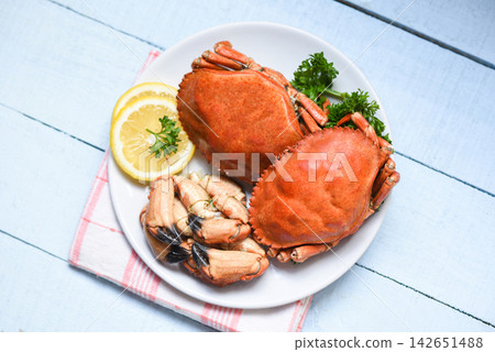 Cooked crab on white plate and wooden background - Seafood boiled red stone crab claw with herb and spices 142651488