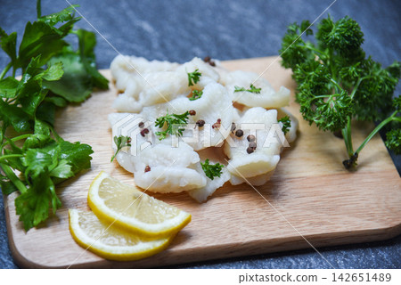 Cooked fish fillet piece with lemon and spices on wooden cutting board background - pangasius dolly fish meat 142651489