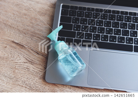 Disinfects the surface of the laptop by sanitizer spray or alcohol gel washing hand hygiene on the working place for quarantine coronavirus covid-19 working from home concept. Disinfects the surface of the laptop by sanitizer spray or alcohol gel washing hand hygiene on the working place for quarantine coronavirus covid-19 working from home concept. 142651665