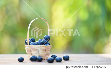 Fresh blueberries fruit in basket on wooden with nature green blur background 142652072