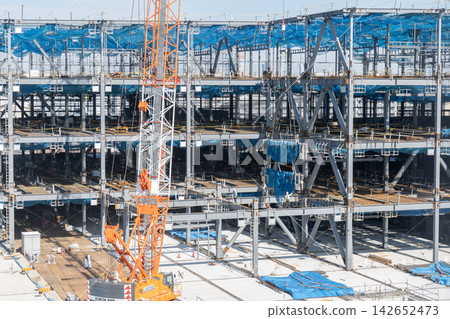 Steel frame construction work: Cranes lift steel frames and workers guide them. 142652473