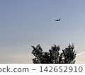 The silhouette of an airplane flying high in the blue twilight sky 142652910