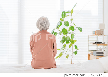 一位老婦人坐在床上,凝視著窗外。我們得以窺見一位老人在暮年所感受到的孤獨和對未來的焦慮。 一位老婦人坐在床上,凝視著窗外。我們得以窺見一位老人在暮年所感受到的孤獨和對未來的焦慮。 142653735