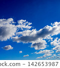elongated fluffy clouds stretch horizontally across a deep blue sky 142653987