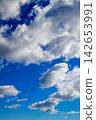 a fluffy cumulus cloud illuminated by sunlight against a bright blue sky 142653991