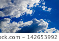 fluffy white clouds in a bright blue sky on a sunny day 142653992