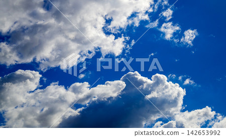 fluffy white clouds in a bright blue sky on a sunny day fluffy white clouds in a bright blue sky on a sunny day 142653992