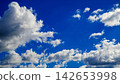 massive white cloud on the left side against a bright blue sky 142653998