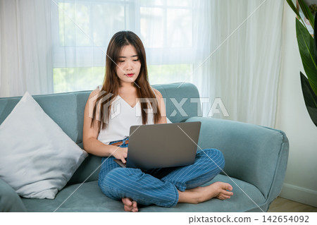Happy woman typing email on notebook computer Happy woman typing email on notebook computer 142654092