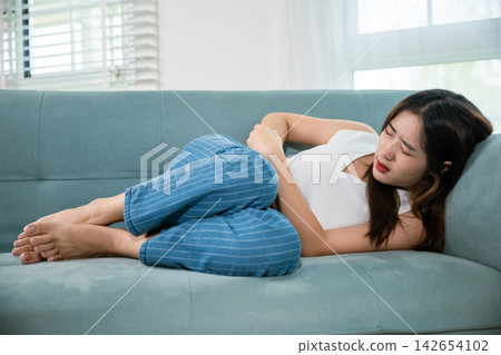 Asian young woman unhappy hands holding on stomach suffering from abdominal pain 142654102
