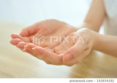 A young woman makes a gesture of scooping with both hands. A young woman makes a gesture of scooping with both hands. 142654292