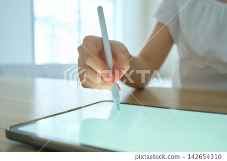 一位年輕女子正在操作平板電腦。 一位年輕女子正在操作平板電腦。 142654310