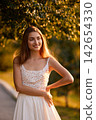 Slavic Woman in Sunlit Garden Wearing White Skirt 142654330