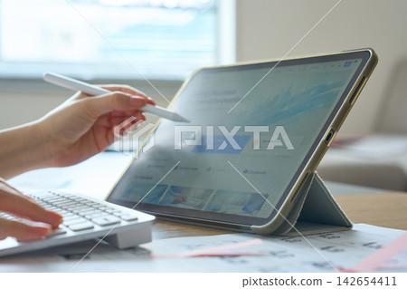A woman's hands as she creates web designs on a tablet. A woman's hands as she creates web designs on a tablet. 142654411