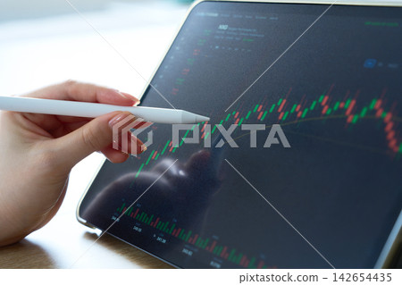 A woman's hands analyzing a stock price chart. A woman's hands analyzing a stock price chart. 142654435