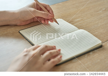 女人的手在筆記本上寫字 女人的手在筆記本上寫字 142654443