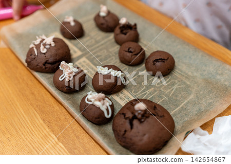 A photo of homemade sweets, featuring chocolate cookies decorated with icing by children. A photo of homemade sweets, featuring chocolate cookies decorated with icing by children. 142654867