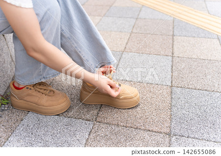 一位年輕女子正在繫鞋帶 一位年輕女子正在繫鞋帶 142655086