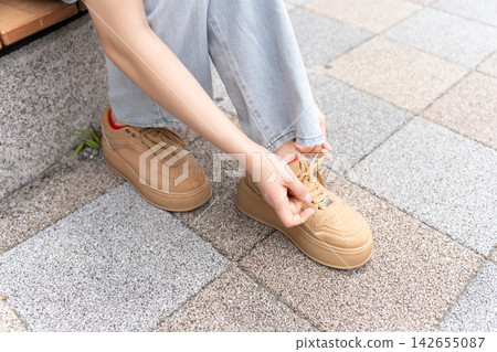 一位年輕女子正在繫鞋帶 一位年輕女子正在繫鞋帶 142655087