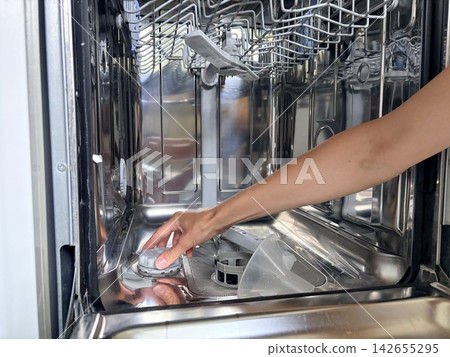 A woman's hands cleaning a dishwasher A woman's hands cleaning a dishwasher 142655295