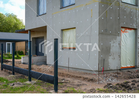 Modern House Facade Under Construction with Exterior Insulation and New Fence Installation Modern House Facade Under Construction with Exterior Insulation and New Fence Installation 142655428