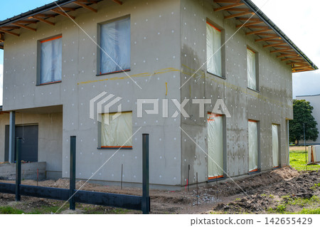 Modern Two-Story House Under Construction with Insulated Facade and Protected Windows Modern Two-Story House Under Construction with Insulated Facade and Protected Windows 142655429