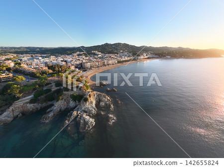Aerial view taken from a drone of the coast of Lloret de Mar, Costa Brava, Spain, early in the morning at sunrise - the sea, beach and coastal hotels Aerial view taken from a drone of the coast of Lloret de Mar, Costa Brava, Spain, early in the morning at sunrise - the sea, beach and coastal hotels 142655824