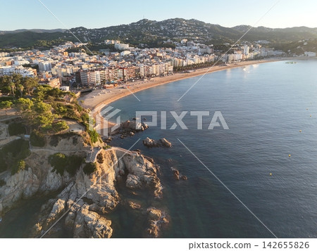 Aerial view taken from a drone of the coast of Lloret de Mar, Costa Brava, Spain, early in the morning at sunrise - the sea, beach and coastal hotels Aerial view taken from a drone of the coast of Lloret de Mar, Costa Brava, Spain, early in the morning at sunrise - the sea, beach and coastal hotels 142655826