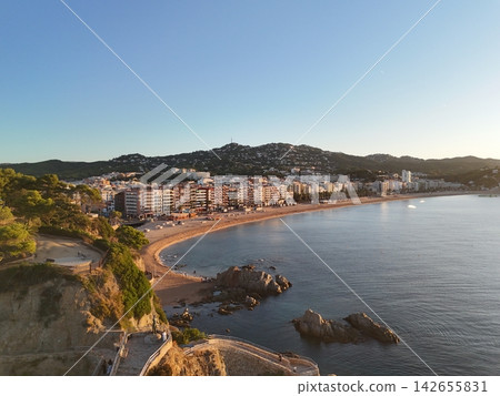 Aerial view taken from a drone of the coast of Lloret de Mar, Costa Brava, Spain, early in the morning at sunrise - the sea, beach and coastal hotels Aerial view taken from a drone of the coast of Lloret de Mar, Costa Brava, Spain, early in the morning at sunrise - the sea, beach and coastal hotels 142655831