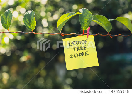 Paper note reading DEVICE FREE ZONE attached to leafy green plant. Suitable for digital detox, screen-free lifestyle technology Paper note reading DEVICE FREE ZONE attached to leafy green plant. Suitable for digital detox, screen-free lifestyle technology 142655956