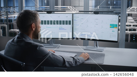 IT Specialist Monitoring Critical Overheating Alert in Large Data Center 142656048