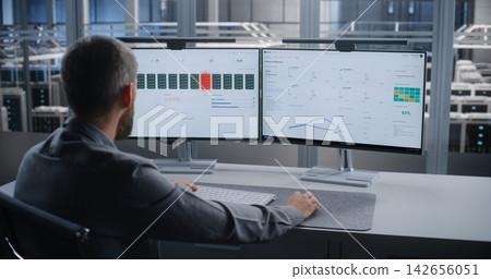 IT Specialist Monitoring Critical Overheating Alert in Large Data Center 142656051
