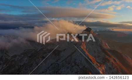 Amazing rocky mountains in clouds at sunset Amazing rocky mountains in clouds at sunset 142656123