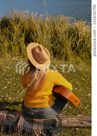 Portrait of smiling caucasian artist plays wooden acoustic guitar in autumnal park. Young songwriter plays string musical instrument hobby outside in nature fall time. Audio music healing Portrait of smiling caucasian artist plays wooden acoustic guitar in autumnal park. Young songwriter plays string musical instrument hobby outside in nature fall time. Audio music healing 142656706