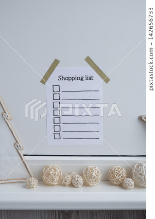Holiday preparation paper note with SHOPPING LIST checklist text. Vision board wall with cozy minimalistic handmade new year Christmas decor Low key festive celebration Holiday preparation paper note with SHOPPING LIST checklist text. Vision board wall with cozy minimalistic handmade new year Christmas decor Low key festive celebration 142656733