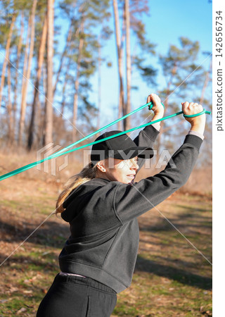 Woman Using Resistance Band for Upper Body Exercise Outdoors Woman Using Resistance Band for Upper Body Exercise Outdoors 142656734