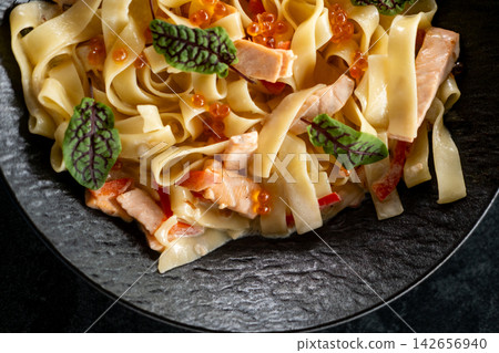 Creamy tagliatelle. Italian cuisine. Appetizing dish with salmon red caviar in sauce. Tasty meal garnished with small sorrel leaves. Creamy tagliatelle. Italian cuisine. Appetizing dish with salmon red caviar in sauce. Tasty meal garnished with small sorrel leaves. 142656940
