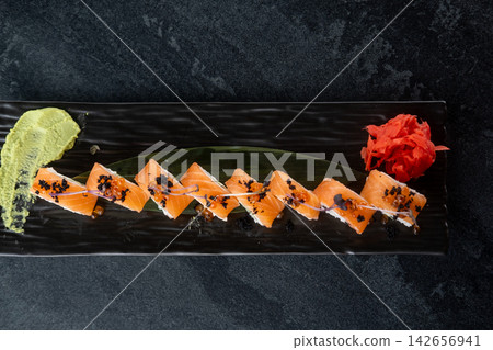 Fish menu. Japanese food. Traditional salmon sushi rolls served with wasabi sauce ginger caviar microgreen on black plate empty space. Fish menu. Japanese food. Traditional salmon sushi rolls served with wasabi sauce ginger caviar microgreen on black plate empty space. 142656941