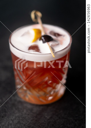 Cocktail mixed. Refreshing beverage. Aroma drink with ice cube skewered olive lemon peel. Served cold new york sour foam in glass. 142656963