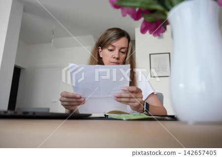 Woman reviewing household bill and expenses at home Woman reviewing household bill and expenses at home 142657405