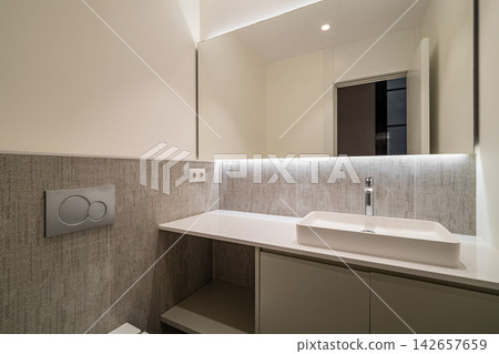 Contemporary bathroom interior featuring white rectangular sink, minimalist vanity cabinet, textured wall tiling, soft warm lighting, neutral finishes and compact elegant layout 142657659