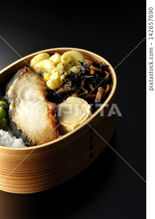 A bento box of grilled silver cod marinated in Saikyo miso, photographed against a black background. A bento box of grilled silver cod marinated in Saikyo miso, photographed against a black background. 142657690