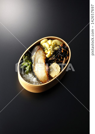 A bento box of grilled silver cod marinated in Saikyo miso, photographed against a black background. A bento box of grilled silver cod marinated in Saikyo miso, photographed against a black background. 142657697
